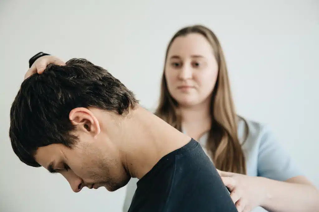 A physiotherapist helps a patient with neck exercises in a clinic setting.