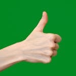 Close-up of a human hand showing a thumbs up sign against a green background.