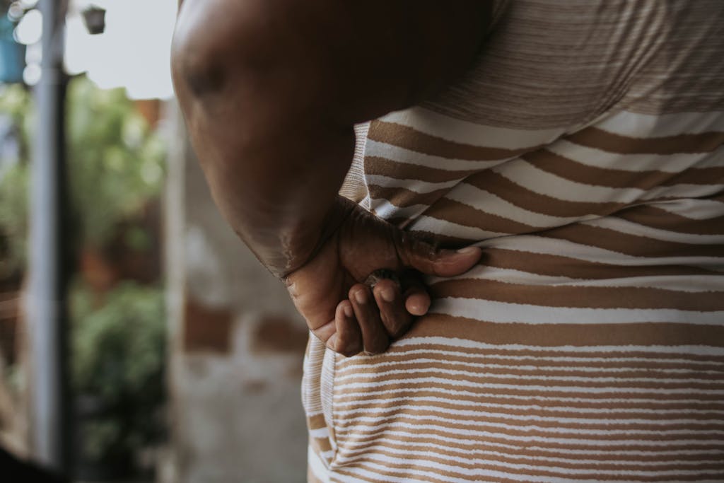 Closeup of a person with hands on hips wearing striped clothing.